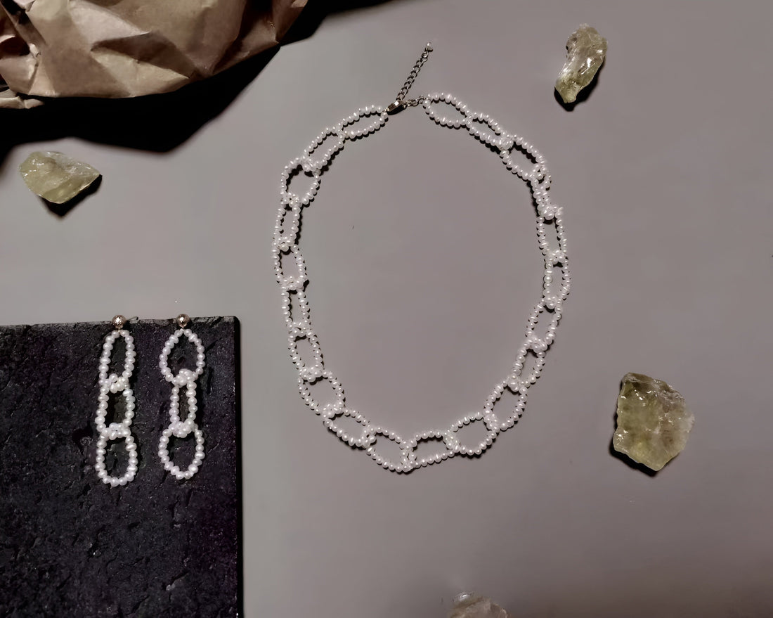  A Timeless Pearl earring pair and necklace placed near gemstones.