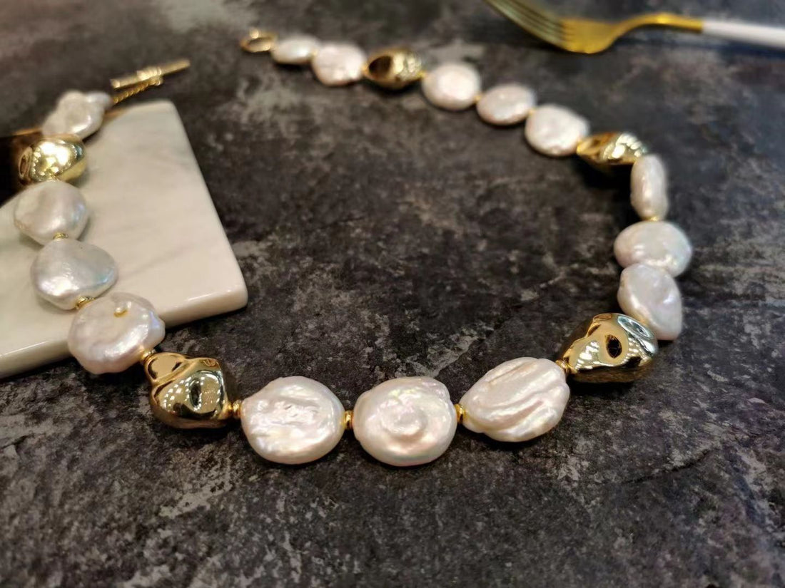 Baroque pearl bracelet with gold accents from Timeless Pearl placed on a dark textured surface.