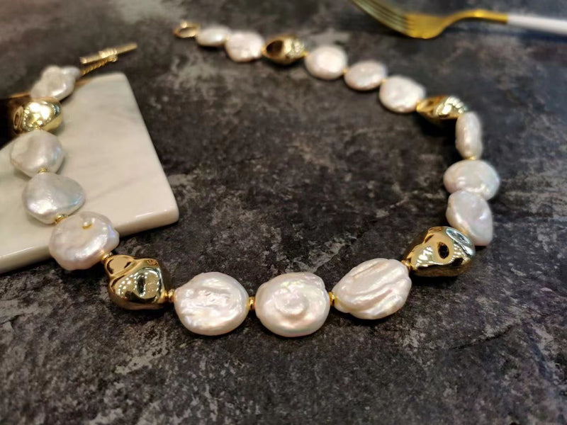 Baroque pearl bracelet with gold accents from Timeless Pearl placed on a dark textured surface.