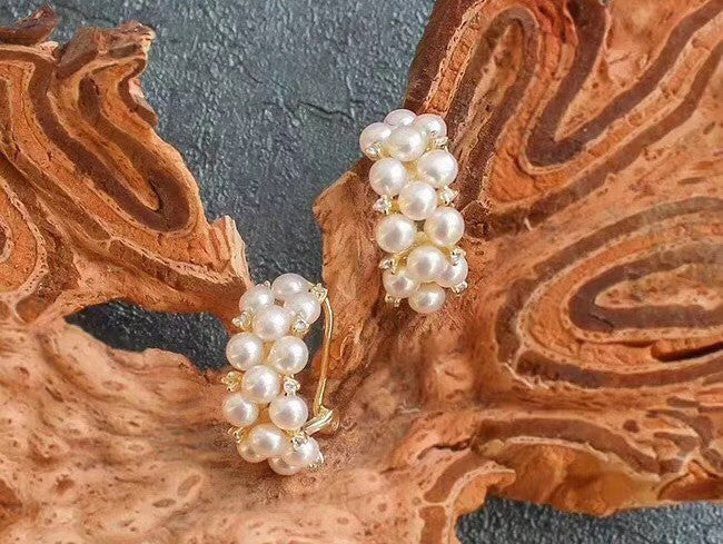 Elegant cluster pearl earrings from Timeless Pearl resting on textured natural wood.
