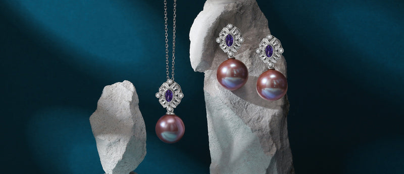 Timeless Pearl Jewelry earring pair hanging on a rock, while a necklace is dangling.