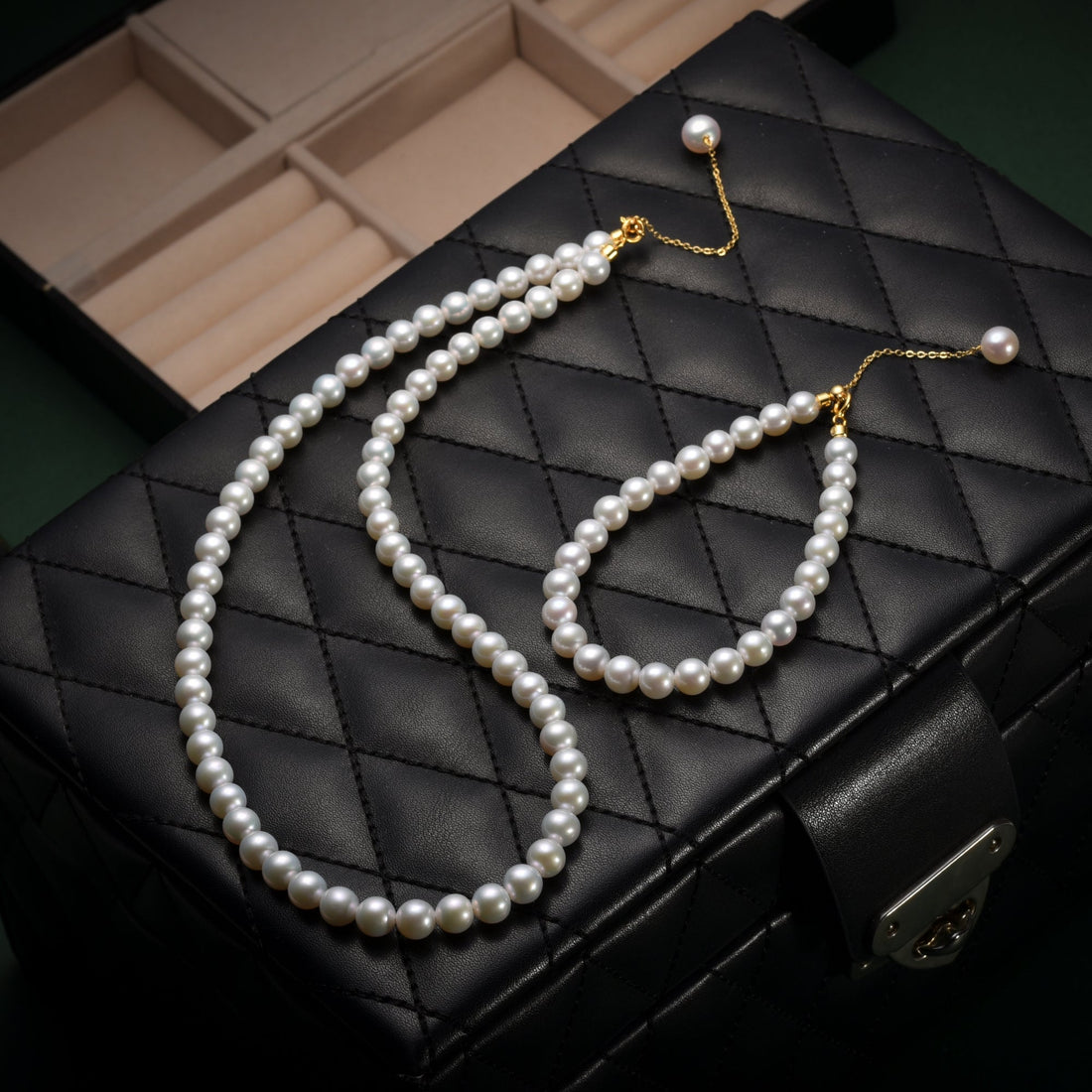 Timeless Pearl necklace and bracelet set with white pearls on a quilted black jewelry box.