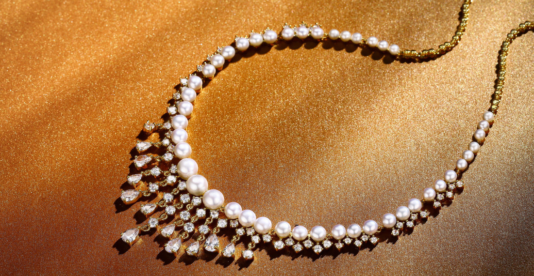 Elegant Timeless Pearl and diamond necklace on a golden background, featuring round pearls and teardrop diamonds.
