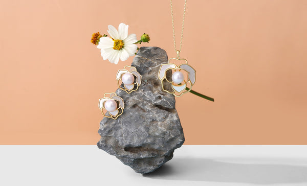Timeless Pearl gold jewelry with pearl and shell floral design on a rock with a flower.