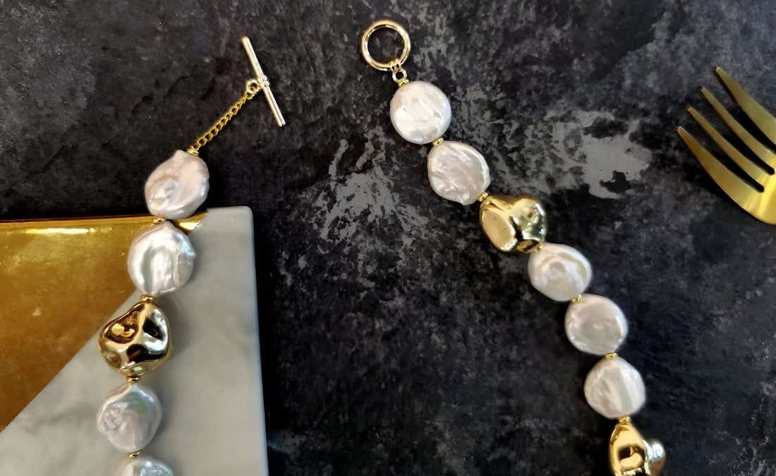  A Timeless Pearl necklace with gold pieces surrounded by a fork and a gift box.