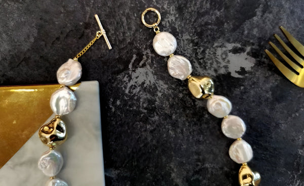  A Timeless Pearl necklace with gold pieces surrounded by a fork and a gift box.