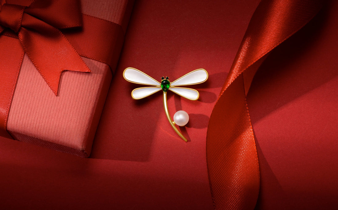 A Timeless Pearl piece surrounded by a tapered red ribbon and gift box.