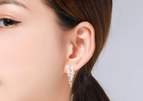 Woman wears cascading pearl and crystal earrings by Timeless Pearl.