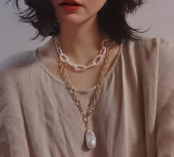Timeless Pearl showcases layered gold chains with a large baroque pearl pendant worn over a neutral linen blouse.