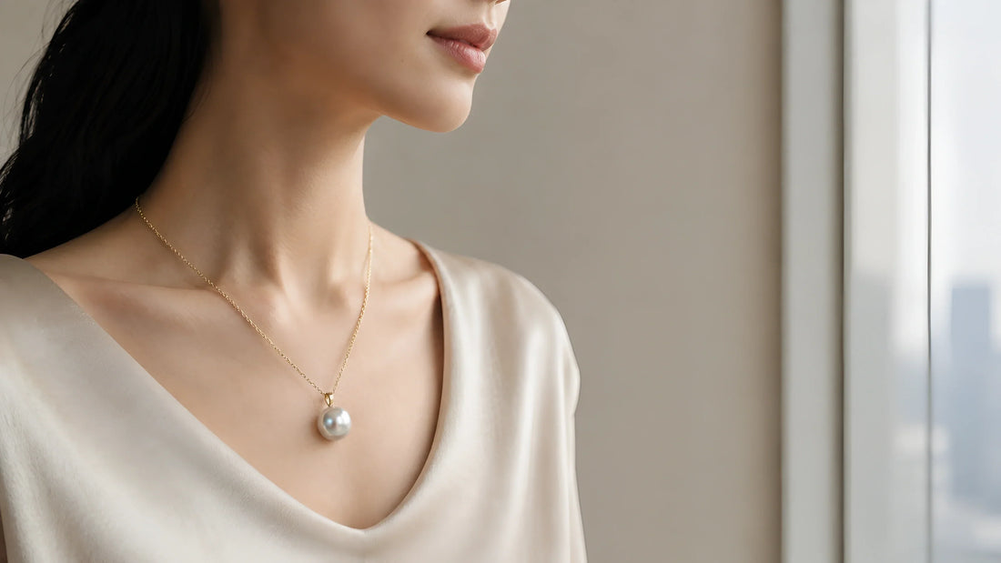 Woman wears a luminous white pearl pendant by Timeless Pearl with an elegant ivory top.