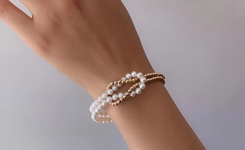 Timeless Pearl layered pearl and gold bead bracelet worn on the wrist.