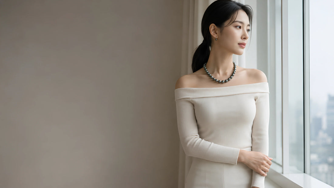 Woman wears a dark pearl necklace and earrings by Timeless Pearl with an elegant ivory dress.