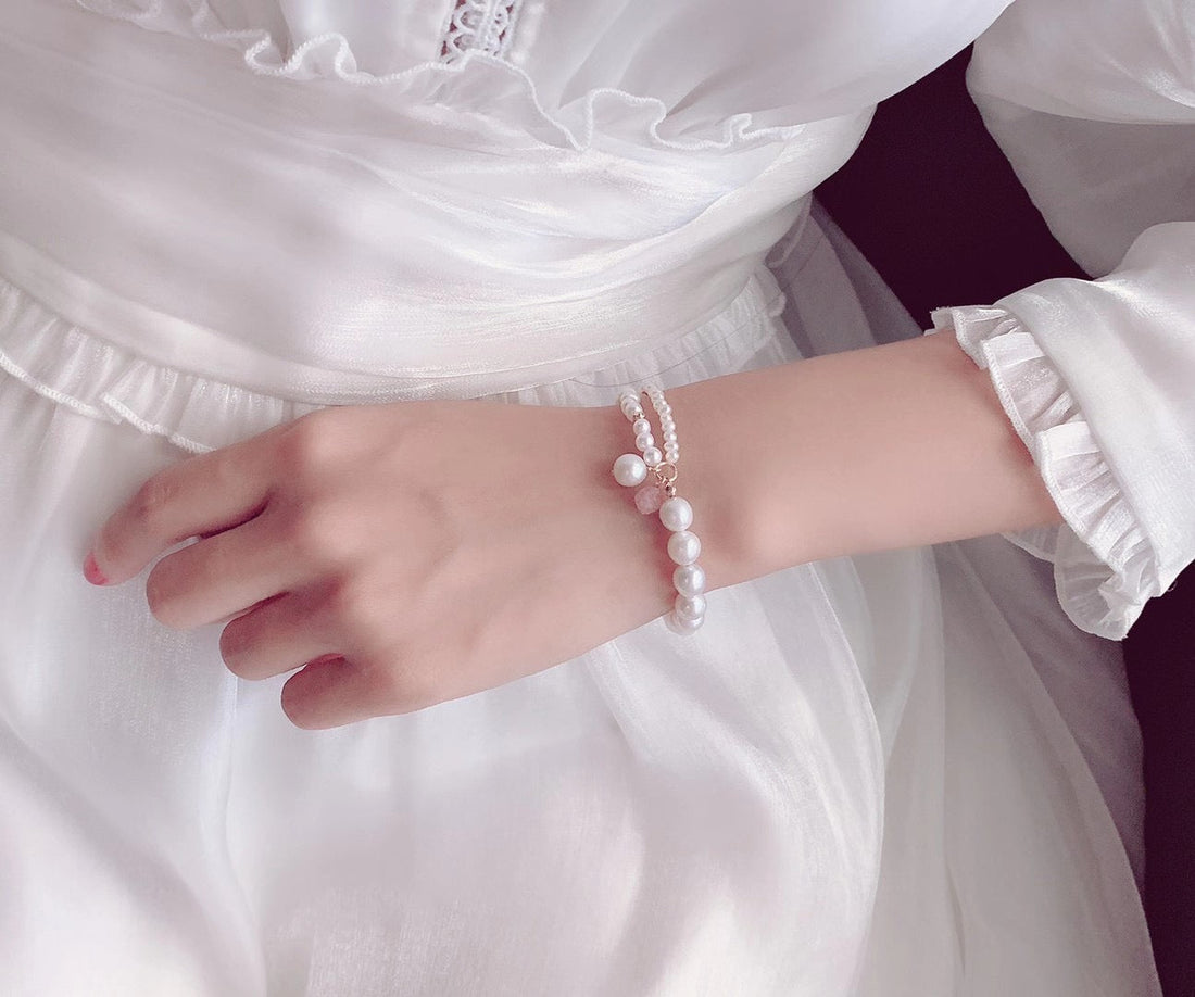  Timeless Pearl layered white pearl bracelet with gold accents worn against a soft, bridal dress.