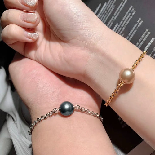Timeless Pearls minimalist pearl bracelets with gold and silver chains, one golden pearl and one black pearl, worn on hands.