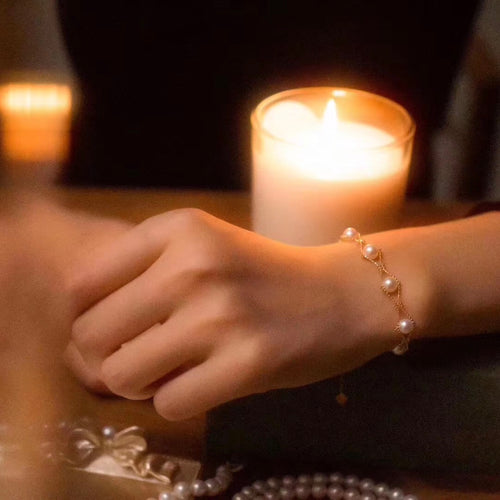 Timeless Pearls delicate gold chain bracelet with round golden pearls, worn by candlelight for an elegant evening look