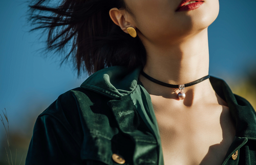 Close-up of a woman wearing a black choker with a pearl pendant by Timeless Pearls.