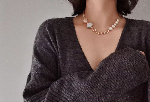Close-up of a person wearing a Timeless Pearls jewelry necklace with white pearls and a rose gold chain, showcasing a chic and elegant look.