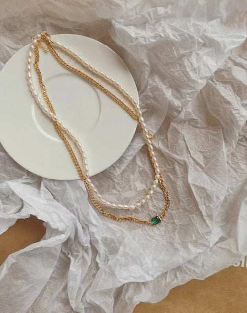 A timeless pearl and gold necklace with an emerald green stone by Timeless Pearls.