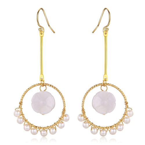 Gold hoop earrings with a carved flower detail and freshwater pearls hanging from the bottom